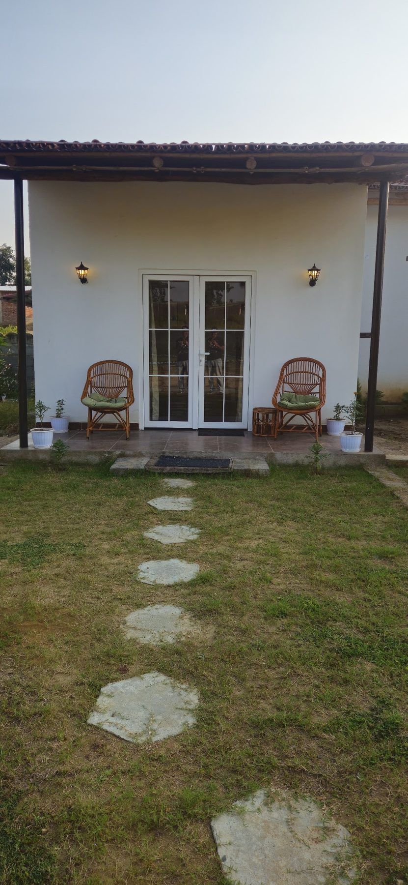 White cottage at Ladigarh with cane chairs on the veranda and a stepping-stone path across the lawn