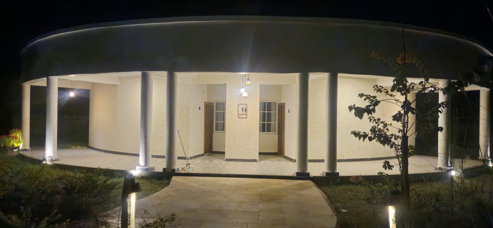 A colonnaded cottage lit at night