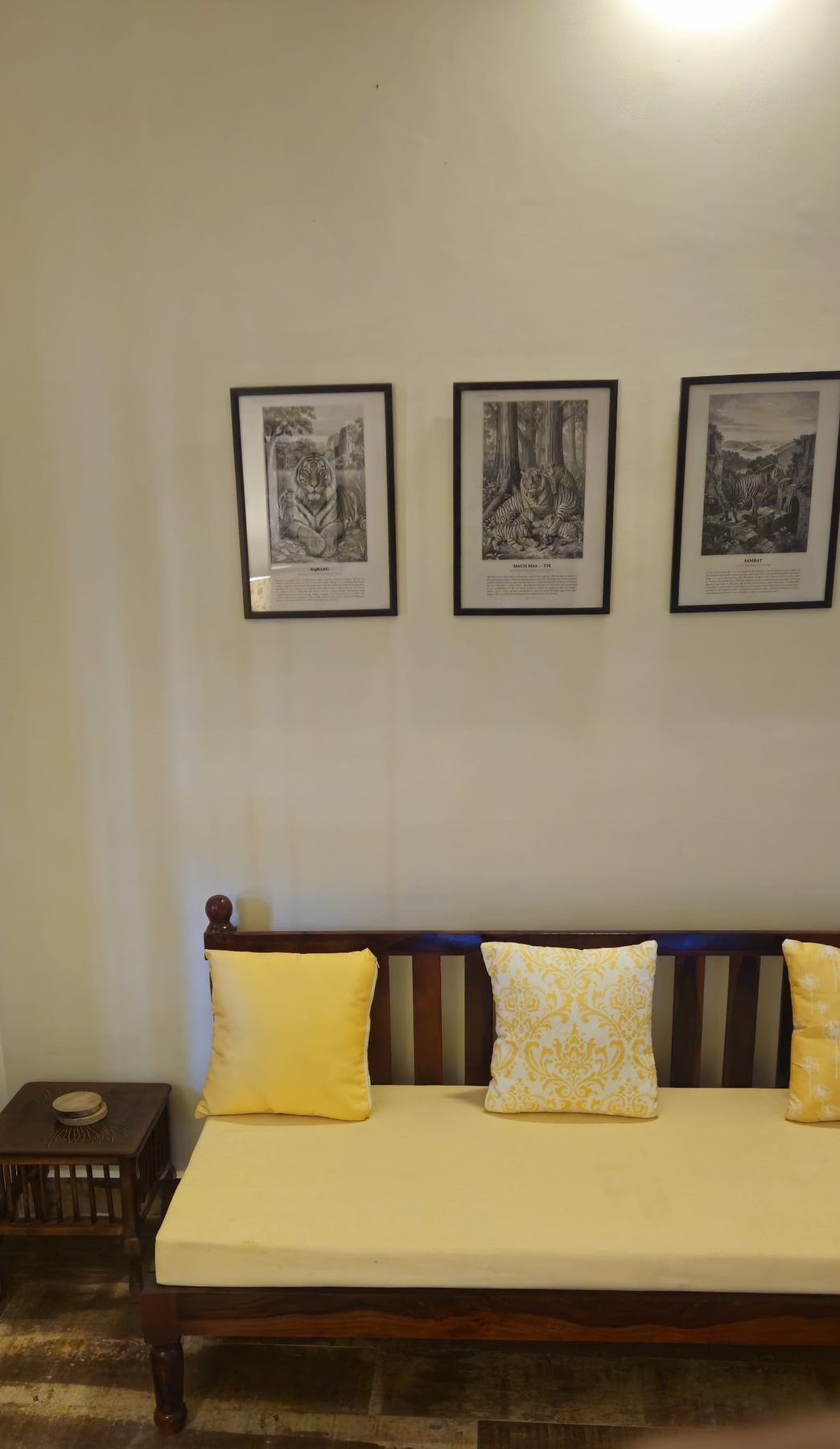 Daybed with yellow cushions under three framed engravings