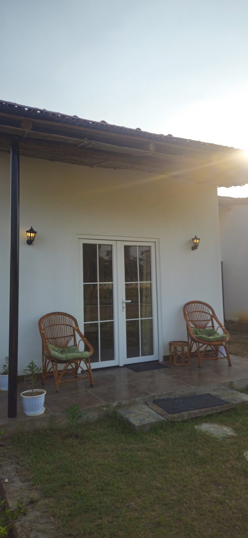 A white cottage with cane chairs on its veranda, morning